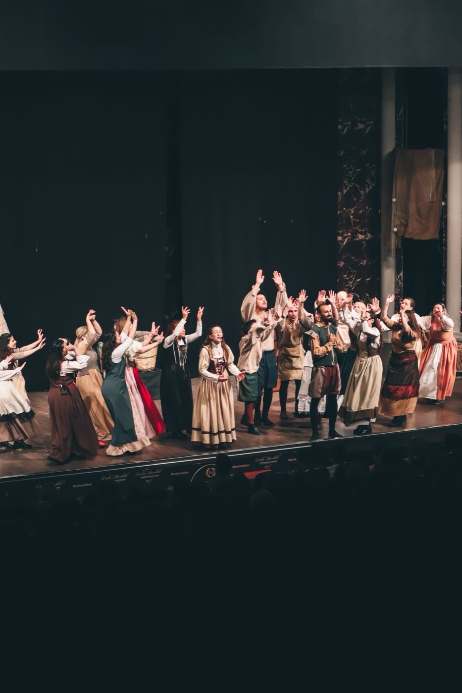 Theatre performers on a lit stage, projecting their voices through a live performance